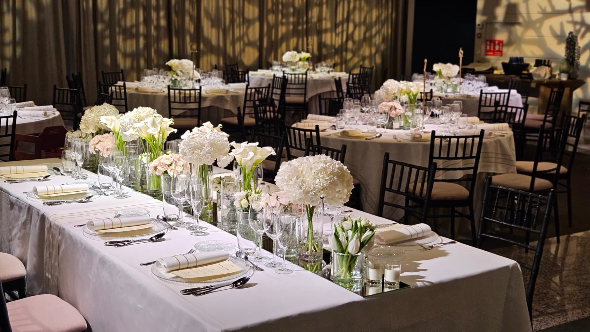 Mesas de banquete de boda con centros de hortensia y calas blancas