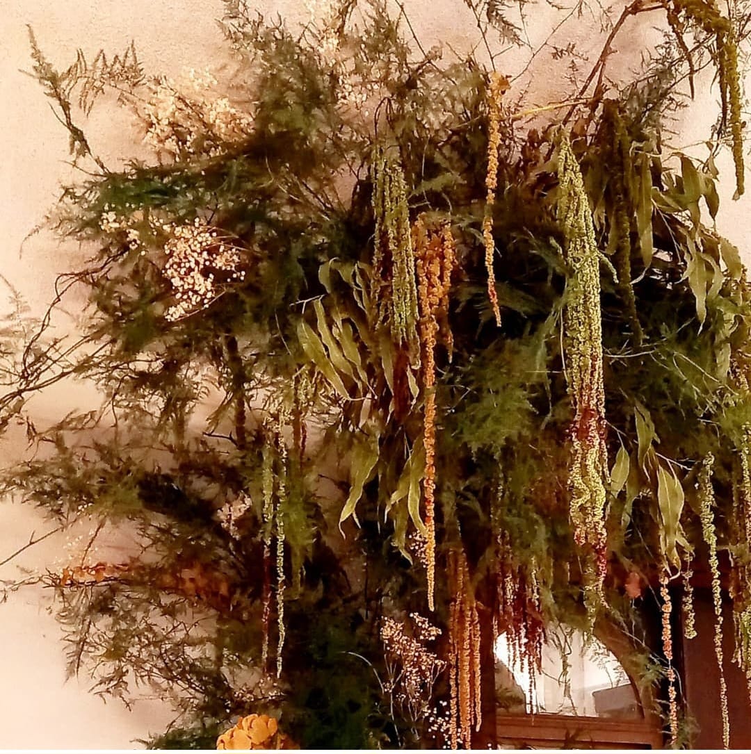 Instalación floral suspendida con verde y amaranto colgante en tonos otoñales
