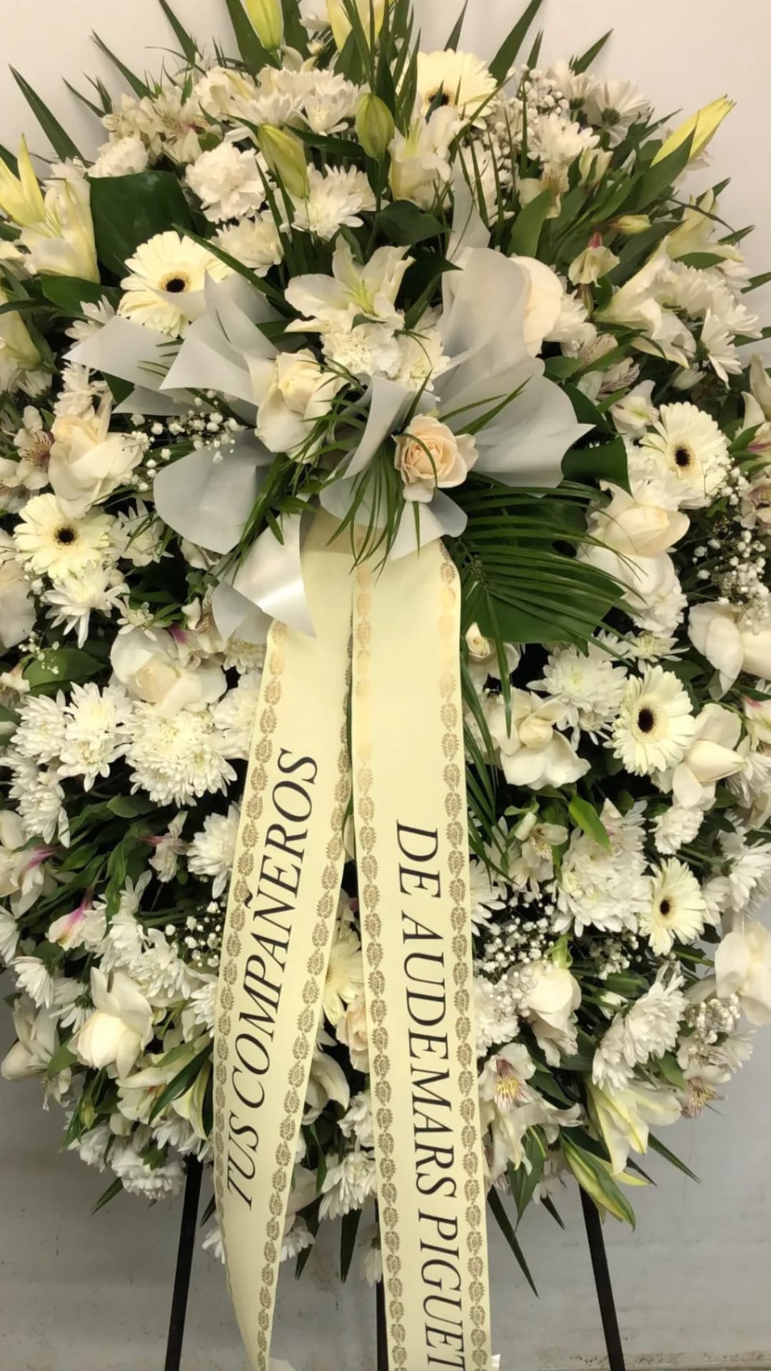 Corona funeraria de flor blanca con cinta de dedicatoria preparada en la floristería