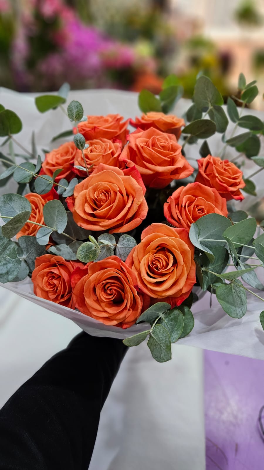 Ramo de rosas naranjas con eucalipto recién compuesto en la floristería